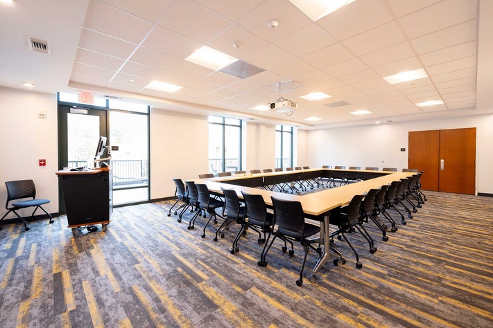 Large Laurel Creek Hall meeting room with tables, rolling chairs and presentation equipment.