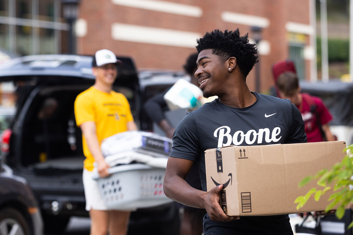 Student carries a packed box during residence hall move-in at App State.
