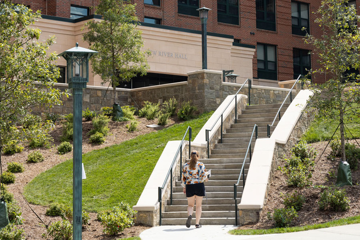 Student walks up outdoor steps toward New River Hall residence hall on App State's campus.