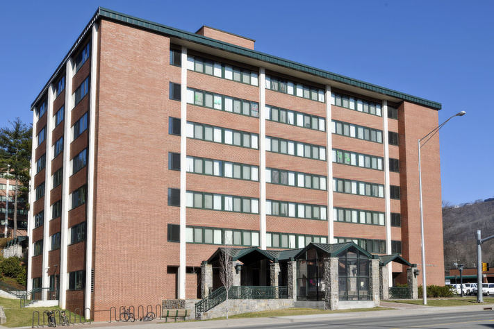 Brick exterior and main entrance of Dogwood Residence Hall with mountains visible behind it