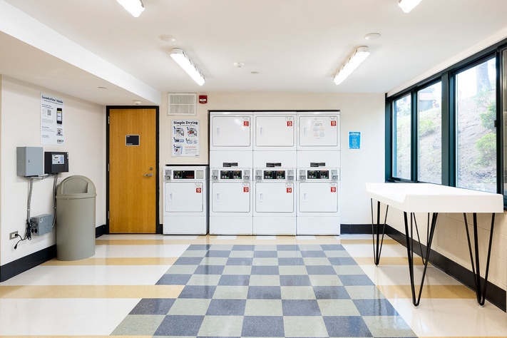 Doughton Hall laundry room with stacked machines, folding tables and large windows