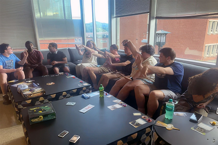 Students play a tabletop game in a residence hall lounge, connecting with peers and building community.