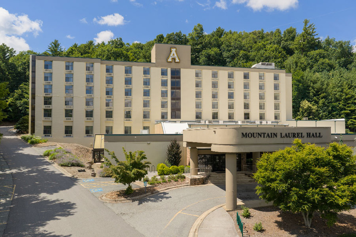 Exterior view of Mountain Laurel Hall at Appalachian State University with residence hall entrance, surrounding trees, and campus roadway.