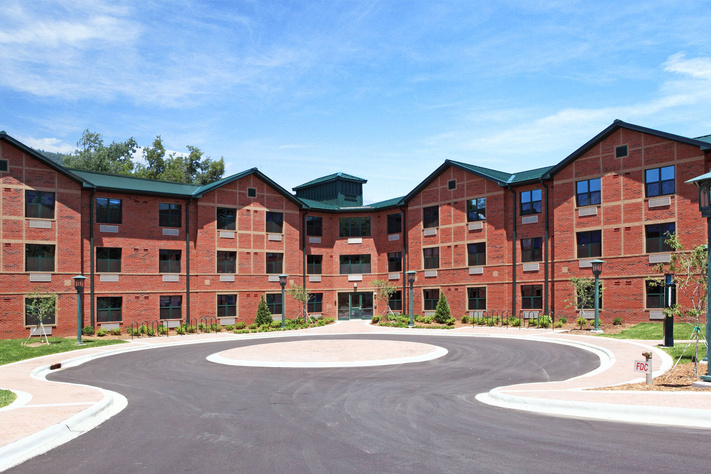 Wide view of Mountaineer Hall’s brick exterior, landscaped entrance and circular drive.