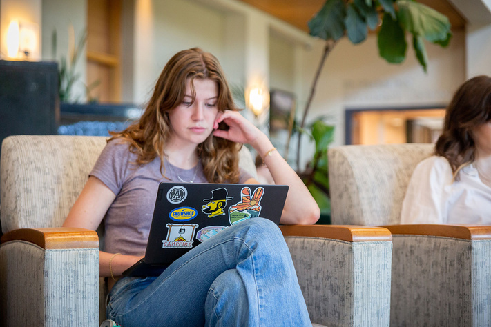 Student using a laptop while seated in the Appalachian State University Plemmons Student Union Solarium.