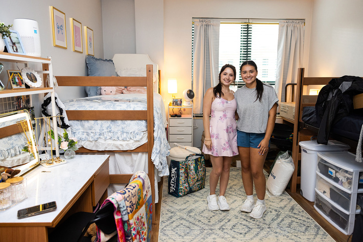 Two students stand together in a decorated shared residence hall room during move-in.