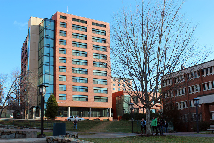 Summit Hall exterior with brick tower, glass stairwell and students walking across campus.