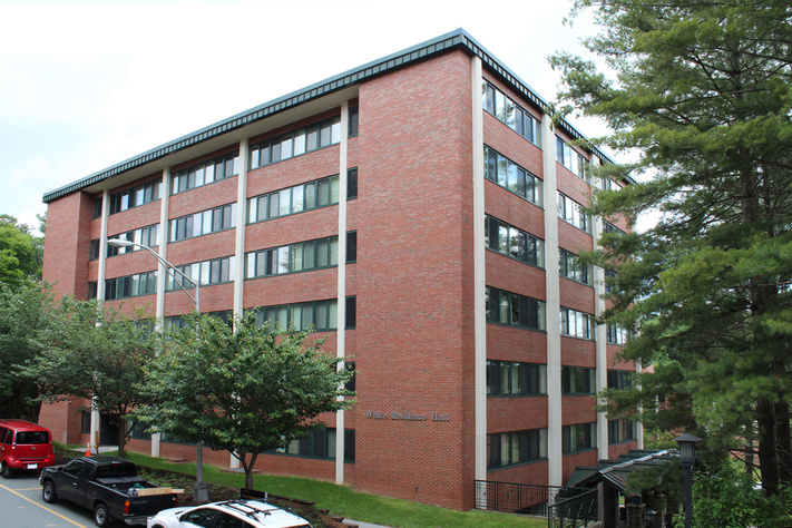 White Hall’s brick exterior viewed from above with trees, parked vehicles and an entrance walkway.