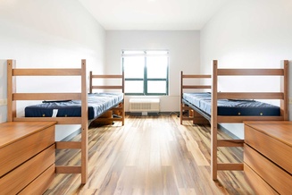 Double room with two raised beds, desks, dressers and a large window.