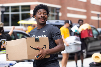 Student carries a packed box during residence hall move-in at App State.