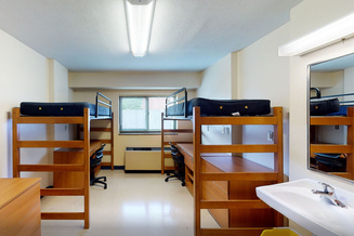 Frank Hall double room with two raised beds, desks, chairs, an in-room sink and window.