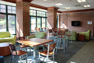 Frank Hall lobby with tables, colorful lounge seating, television and large windows