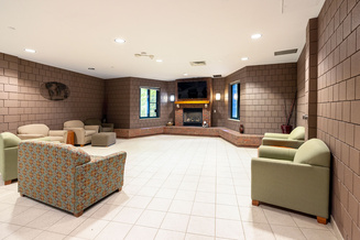 Living Learning Center lobby lounge with armchairs, a fireplace and wall-mounted television.