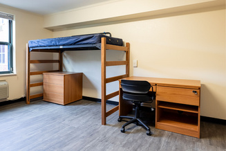 Mountaineer Hall room with a lofted bed, desk, chair, dresser and window.